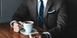 man holding cup filled with coffee on table