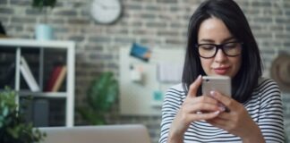 a woman wearing glasses looking at her cell phone