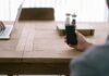 person holding smartphone in front of brown table