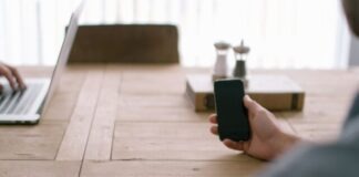 person holding smartphone in front of brown table