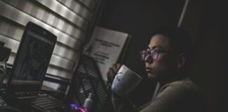 man holding mug in front laptop computer