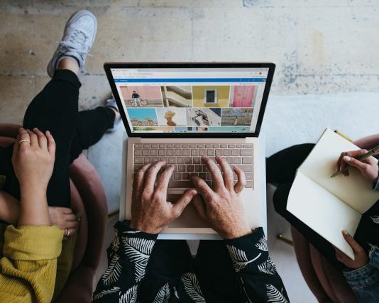 5 Ways Technology Makes Marketing More Powerful person using microsoft surface laptop on lap with two other people