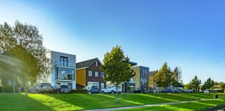 white and brown house near green grass field and body of water during daytime