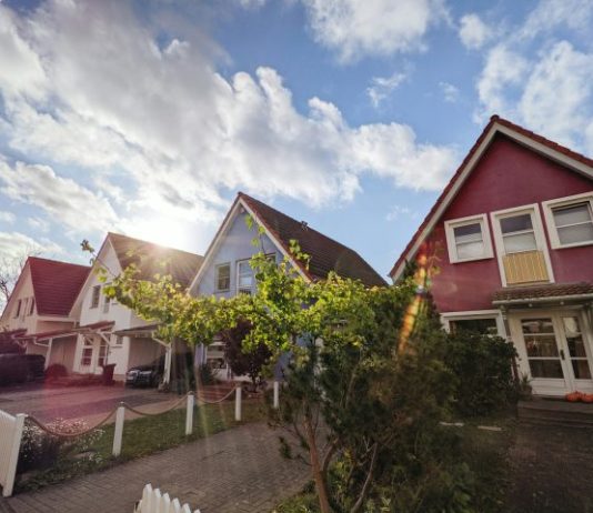 green trees near red and white house under blue sky during daytime