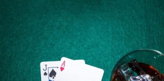 Jack of spade and heart ace playing card with whiskey glass on poker table