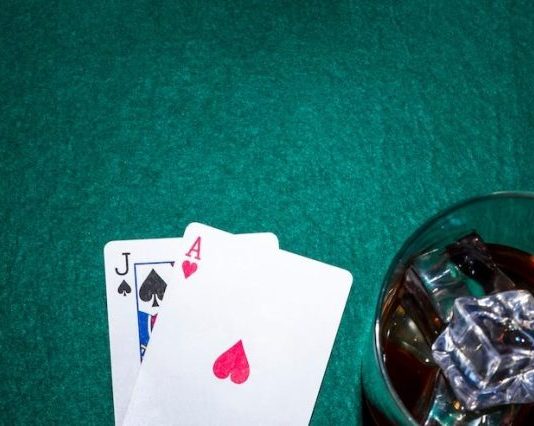 Jack of spade and heart ace playing card with whiskey glass on poker table