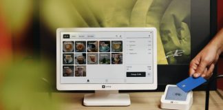 A person is holding a credit card in front of a computer