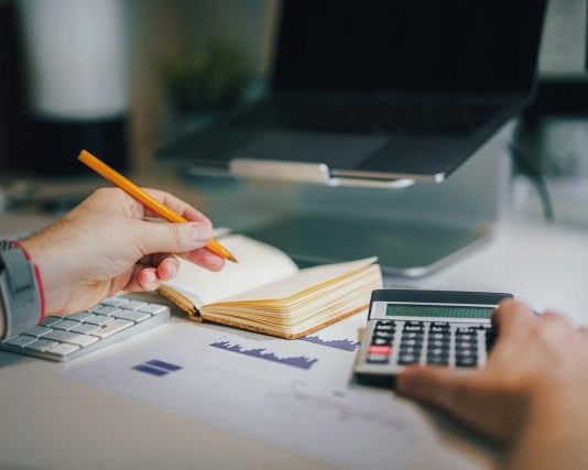 a person sitting at a desk with a calculator and a notebook