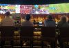 a group of people sitting at a bar watching tv