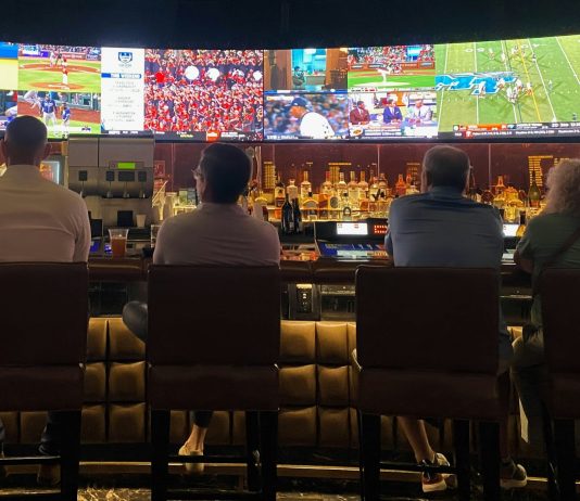 a group of people sitting at a bar watching tv