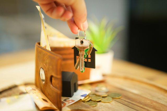 Photo by Jakub Żerdzicki Hand holding keys with house charm and wallet.