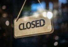 A closed sign hanging from a glass door