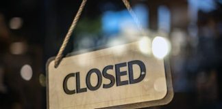 A closed sign hanging from a glass door