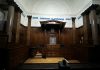 The Benefits of Settling Out of Court an empty courtroom with wooden paneling and columns