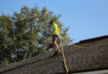 The Importance Of Certification In Finding The Right Roofing Company a man on a roof working with a rope