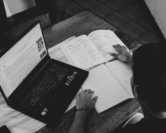 grayscale photo of person holding book