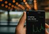 5 Marks of Successful Investors a person holding up a cell phone with a stock chart on it
