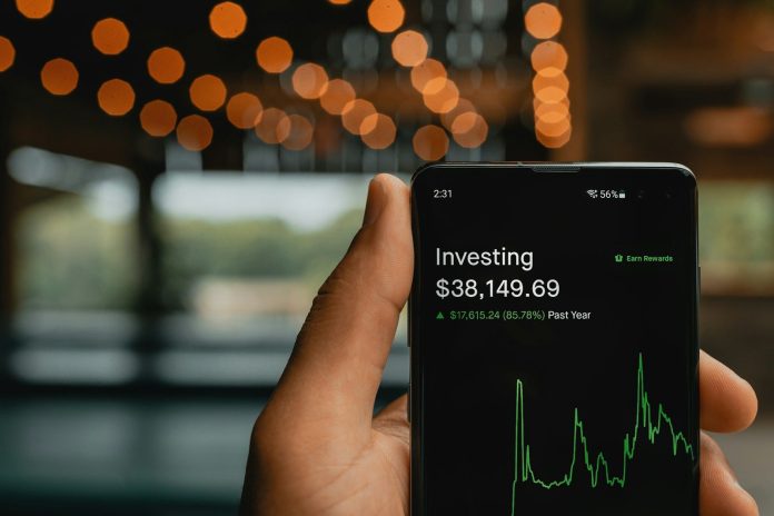 Photo by PiggyBank a person holding up a cell phone with a stock chart on it