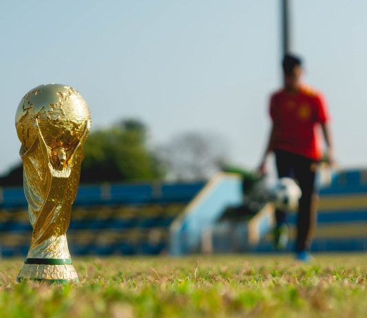 selective focus photography of gold-colored trophy on grass field during daytime